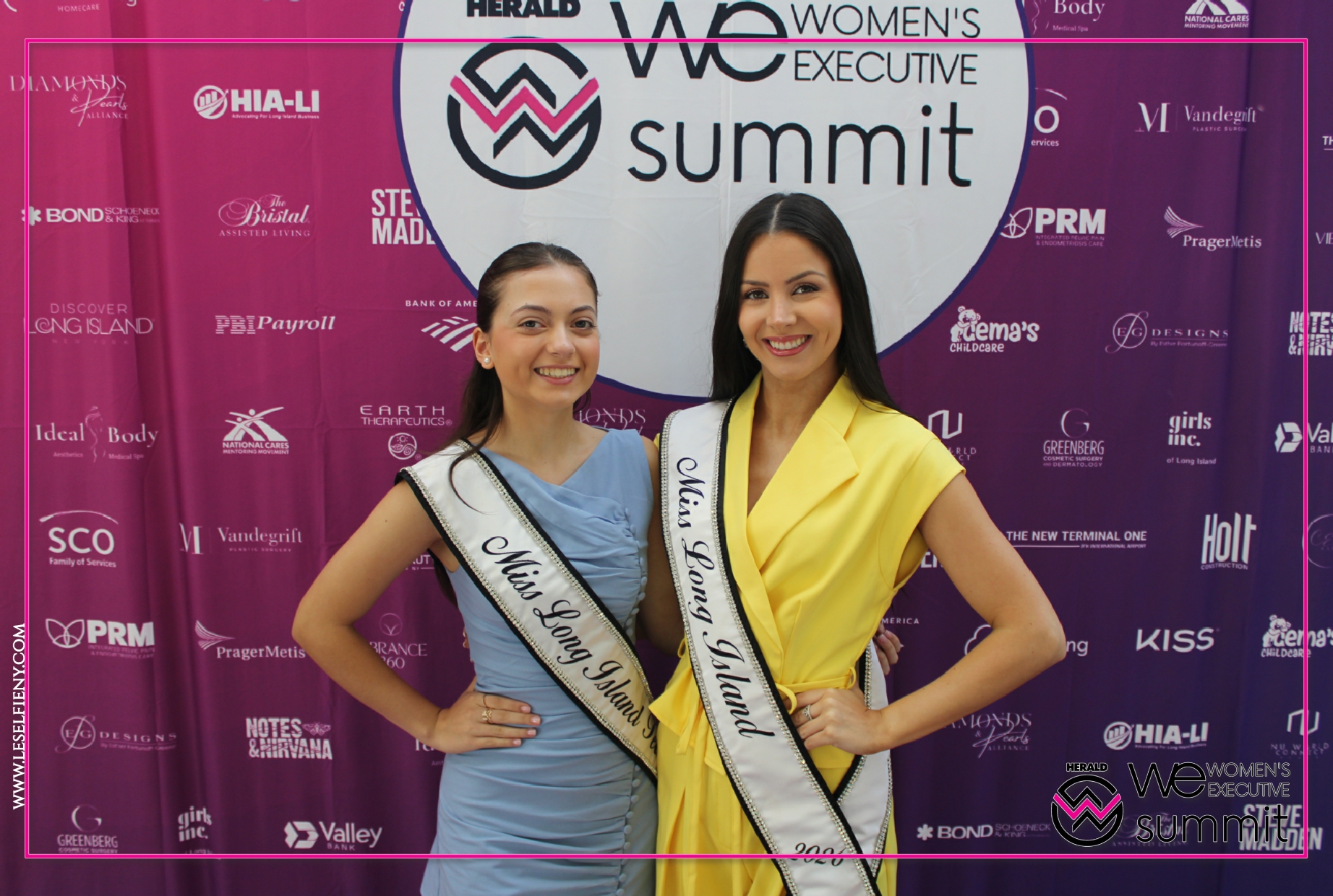 Two smiling women wearing sashes for Miss Long Island and Mrs. Long Island stand together in front of a WE Summit backdrop with logos.