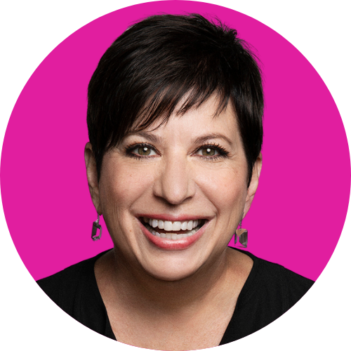 Head-and-shoulders portrait of a smiling woman with short dark hair and a bright pink background, wearing earrings.