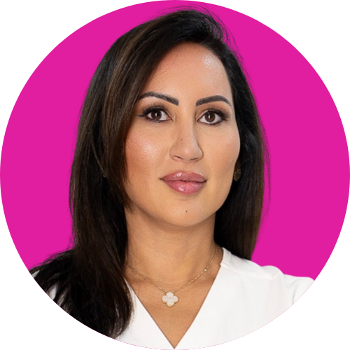 Professional portrait of a woman with dark hair and a white blouse against a bright pink circular background on a clean studio backdrop.