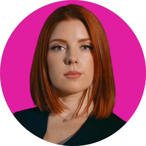 Portrait of a woman with straight red hair and a subtle smile, wearing a dark top, against a bright pink circle behind her.