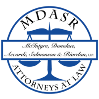 Circular law firm logo featuring blue scales of justice, outer text 'ATTORNEYS AT LAW' and banner with 'McIntyre, Donohue, Accardi, Salmonson & Riordan, LLP'