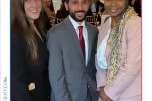 Three professionals in formal attire pose together at a gala event, with a crowd in the background and Top Lawyers branding above the photo.