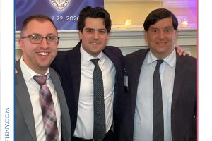 Three men in business suits posing together at a legal awards event, with a 'Top Lawyers of Long Island' banner in the background.