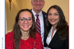 Three professionally dressed people smiling for a group photo at the Top Lawyers of Long Island event, with the logo banner above them.