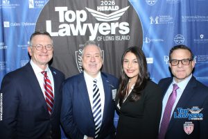 Group of four professionals in suits posing at the 2026 Top Lawyers of Long Island event against a blue sponsor backdrop.