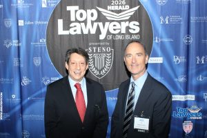 Two suited men posing at a legal awards backdrop that reads 'Top Lawyers of Long Island' with sponsor logos visible behind them, 2026 event. The man on the right wears a name badge labeled 'Honoree'.