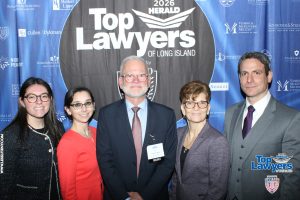 Five professionals pose for a photo at the 2026 Top Lawyers of Long Island event in front of a blue sponsor backdrop.