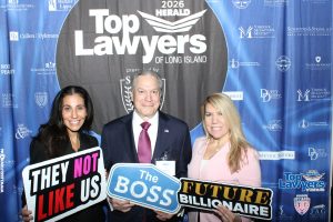 Three people pose at a law awards backdrop, holding oversized protest-style signs with bold messages like 'THEY NOT LIKE US' and 'FUTURE BILLIONAIRE'.