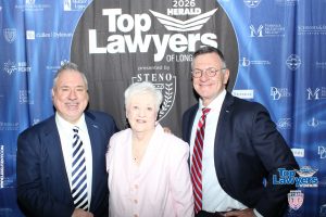Three professionally dressed individuals posing together in front of a 'Top Lawyers' event backdrop.