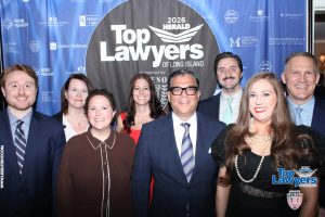 Group of professionally dressed people posing for a photo at the 'Top Lawyers of Long Island' event in front of a blue sponsor backdrop.