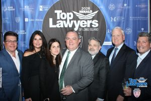Group of seven professionals posing in front of a blue 'Top Lawyers of Long Island' backdrop at a formal event.