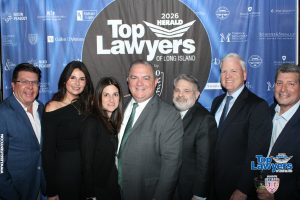Group of smiling professionals posing at the 2026 Top Lawyers of Long Island event in front of a sponsor-laden blue backdrop.