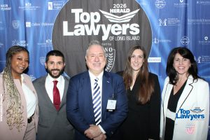 Five professionals pose for a photo at the Top Lawyers of Long Island event, with a blue sponsor backdrop featuring logos.