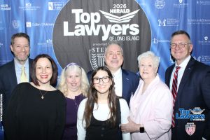 Group of smiling professionals posing at a Law event backdrop reading 'Top Lawyers of Long Island'