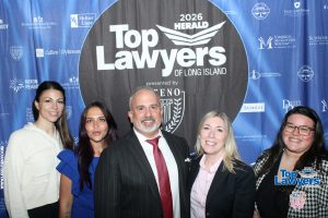 Group of five professionals posing in front of a blue backdrop with 'Top Lawyers of Long Island' logo.