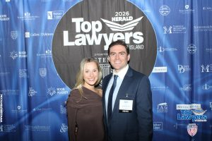 Two smiling attendees pose together at a law-industry event in front of a blue 'Top Lawyers' backdrop with sponsor logos.