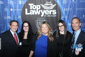 Five professionals in formal wear posing in front of a blue 'Top Lawyers of Long Island' backdrop.