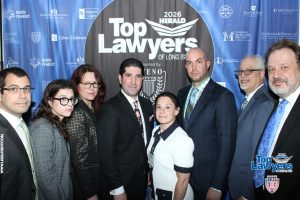 Group of professionals posing for a photo at the Top Lawyers of Long Island event in front of a blue banner backdrop.