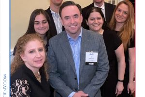 Group of professionals posing together at a legal awards event, wearing business attire, with a central man wearing a nametag that says HONOREE.