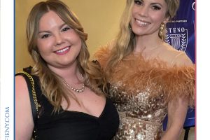 Two smiling women posing together at a formal event for Top Lawyers of Long Island, one in a black dress and the other in a sparkly gold gown with feather accents.