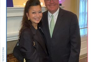 Two well-dressed adults posing for a photo at a Top Lawyers of Long Island event, with a neon awards sign in the background.