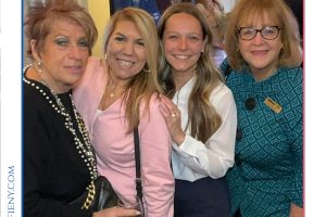Four women smile for a photo at a legal awards event, with a blue 'Top Lawyers of Long Island' backdrop behind them.