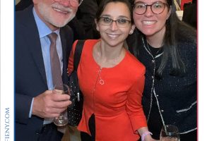 Three smiling attendees pose for a photo at a legal event, with drinks in hand, in front of a 'Top Lawyers of Long Island' frame.