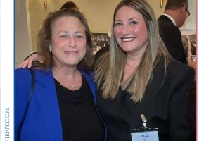 Two women smiling for a photo at a formal event, one in a blue blazer and the other in black, wearing a name badge (Top Lawyers of Long Island event).