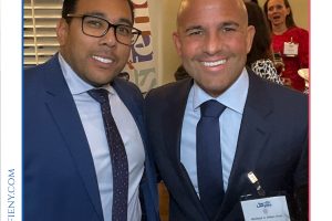 Two men in dark suits smiling at a formal awards event, with a 'Top Lawyers of Long Island' banner above them and name badges visible on their jackets.