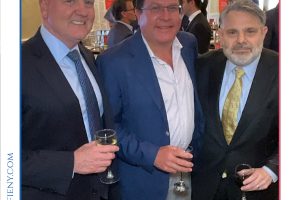 Group photo of three men in business attire at a formal event, each holding a glass of champagne, smiling for the camera at a networking reception (Top Lawyers of Long Island).
