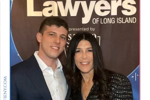 Two people posing in front of a 'Top Lawyers of Long Island' banner at a 2026 Herald event, smiling for the camera.