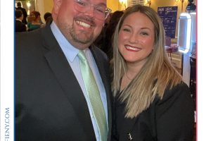 Two people in formal attire pose for a photo at a gala, with 'Top Lawyers of Long Island' branding in the background.