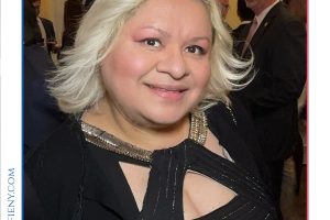 Smiling woman in a black dress with a gold necklace at the 2026 Top Lawyers of Long Island event.