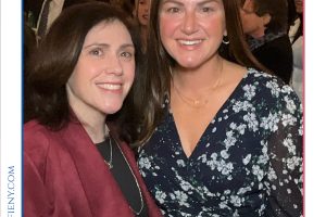Two women smiling for a photo at a formal awards event, with Top Lawyers of Long Island branding in the background.