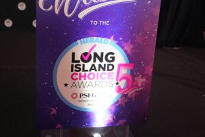 Podium sign on a stage reading 'Welcome to the Long Island Choice Awards 5th Anniversary' with a purple starry background.