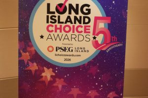 Poster on a stand announcing the Long Island Choice Awards 5th Anniversary, with a purple starry background and circular logo centerpiece.