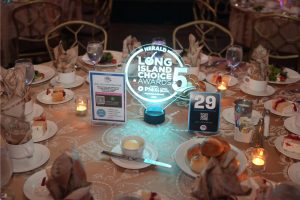 Round banquet table with a glowing 'Long Island Choice Awards' centerpiece and a blue 29 table card among plates and folded napkins.