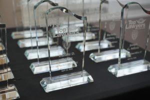 Crystal glass awards with 'Top Lawyers' text on a black table display, reflecting light in multiple angles.