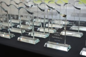 Crystal glass trophies with 'Top Lawyers' etched on them, lined up on a black table at an awards event.