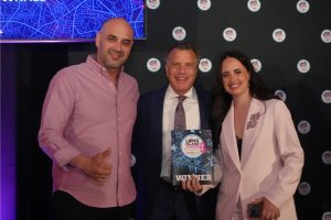 Three people posing at an award ceremony; center man holds a 'WINNER' plaque with Long Island Choice Awards logo behind them.