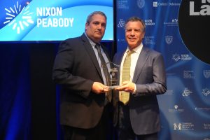 Two men in suits pose with a glass award at a Nixon Peabody event.