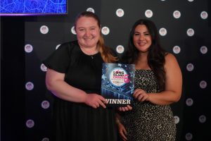 Two smiling women pose together, holding a Long Island Choice Awards 'WINNER' certificate at an awards event backdrop Photo shows the two winners in front of a dark step-and-repeat.