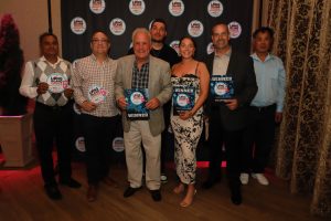 Group of six people posing with winner plaques at a Long Island Choice Awards backdrop.