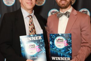 Two men in formal attire pose with Long Island Choice Awards 'WINNER' plaques in front of a branded backdrop.