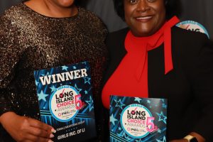 Two smiling women in formal attire pose with WINNER certificates at a Long Island Choice Awards backdrop.