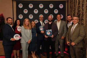 Group of ten suited professionals posing with award plaques at a Long Island Choice Awards backdrop.