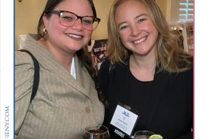 Two women smiling at a Top Lawyers of Long Island event, each holding a drink and wearing name badges.