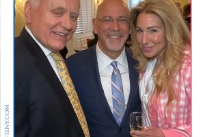 Three adults in formal attire posing at a reception at a Top Lawyers event, with a woman holding a champagne glass and pink bag.