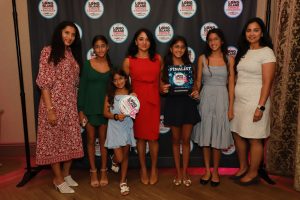 Group of seven women posing on a step-and-repeat backdrop at the Long Island Choice Awards, with two holding awards/signs showing 'Finalist' and logos.