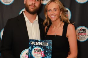 Two people in formal attire pose with a blue winner plaque at the Long Island Choice Awards backdrop.